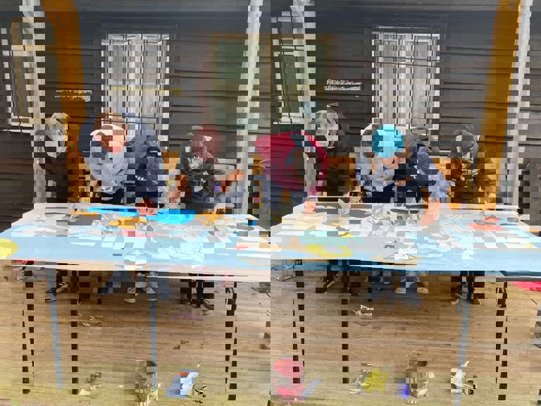 four people leaning over a table painting a mural