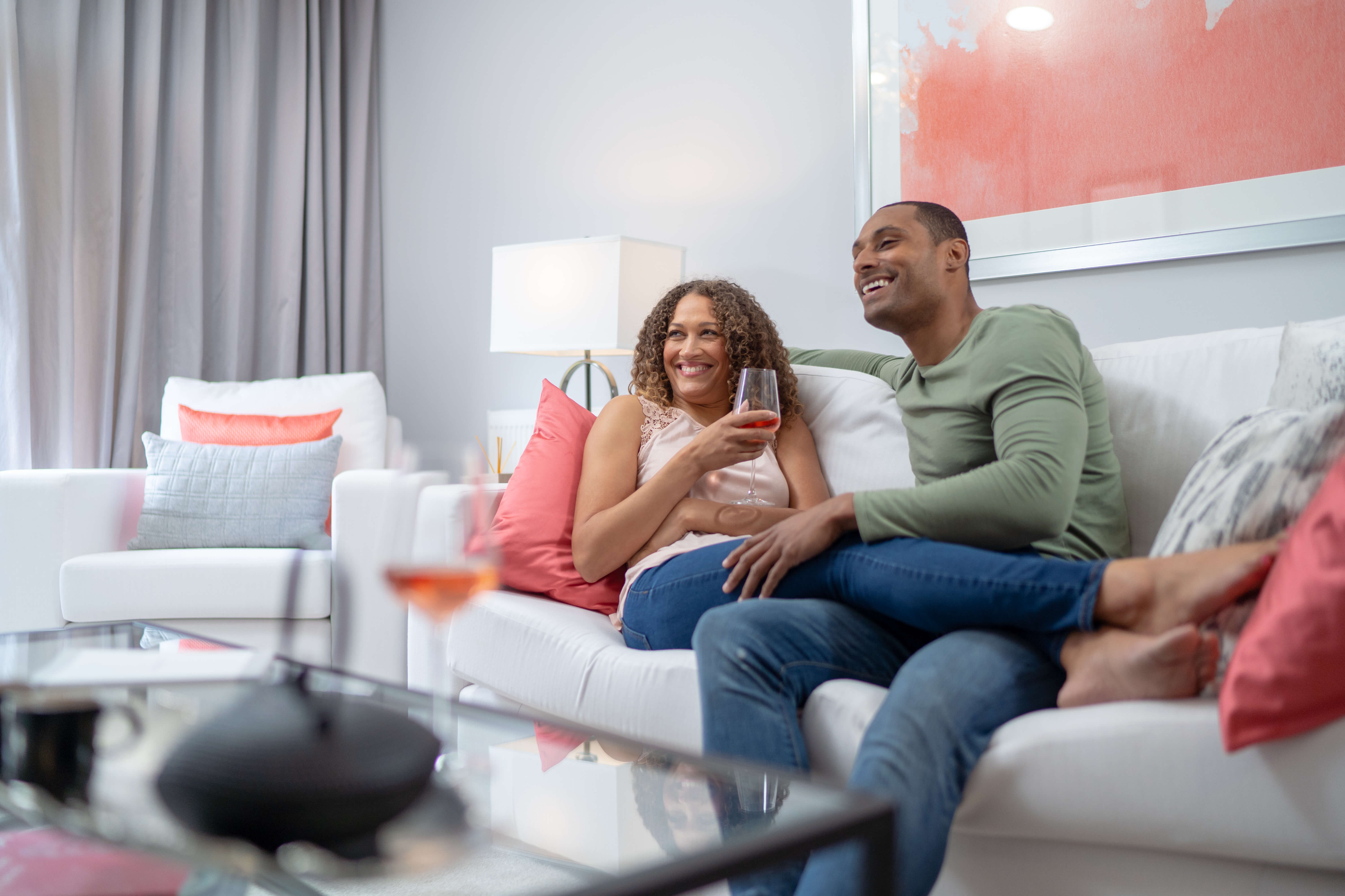 Couple sitting on the couch laughing drinking wine