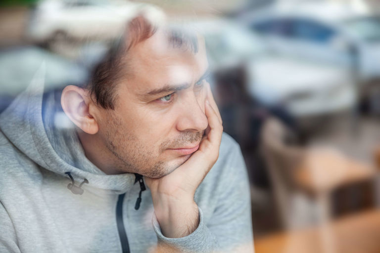 man in grey sweater looking out of window