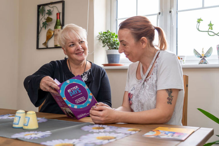 two ladies looking at a Better Days booklet