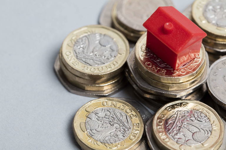 red monopoly house on a pile of coins