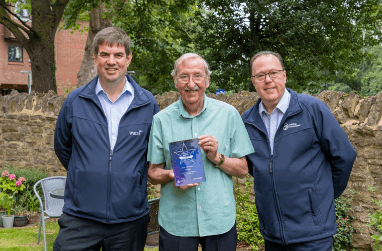 man standing next to another two men holding a thriving communities award