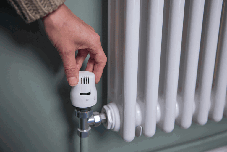 hand turning up temperature on a heater