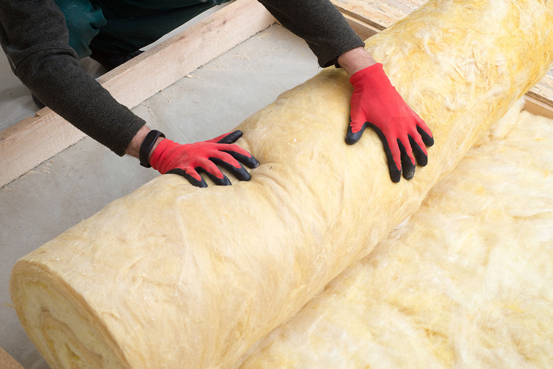 two hands with red gloves rolling up insulation padding