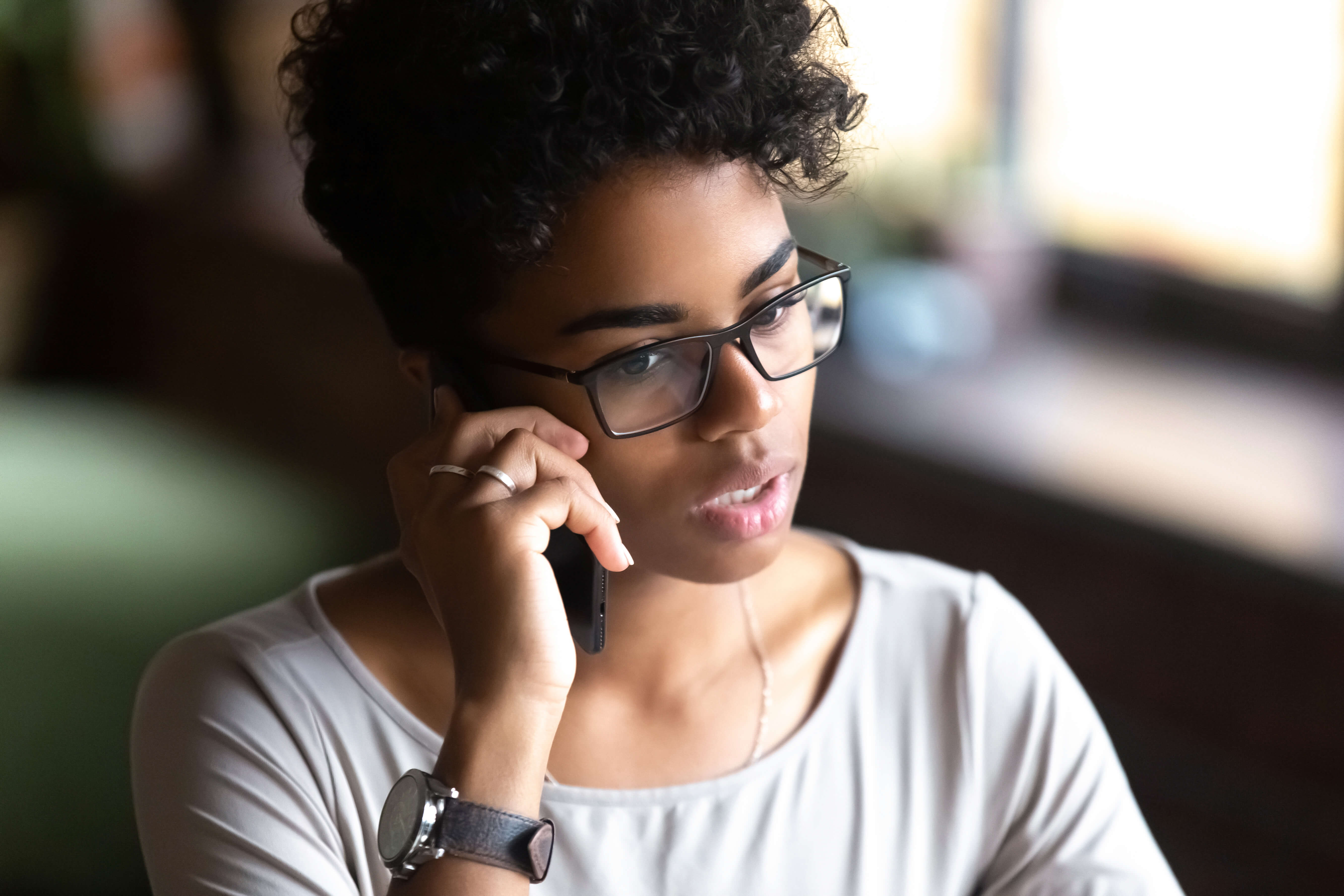 lady wearing black glasses and a white shirt on her mobile phone