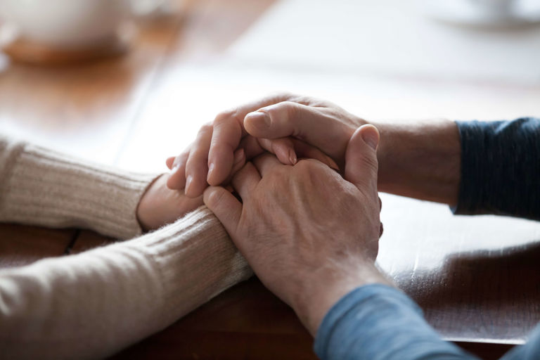 Image of two people holding hands supportively