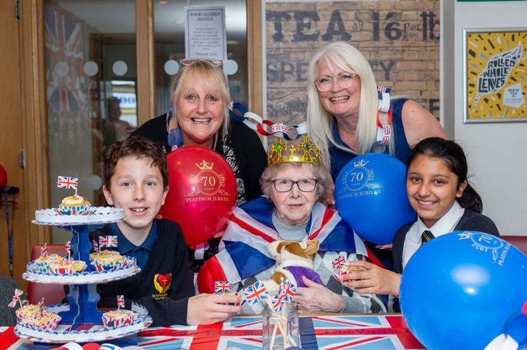 group of ladies and kids sitting at a table with union jack cupcakes