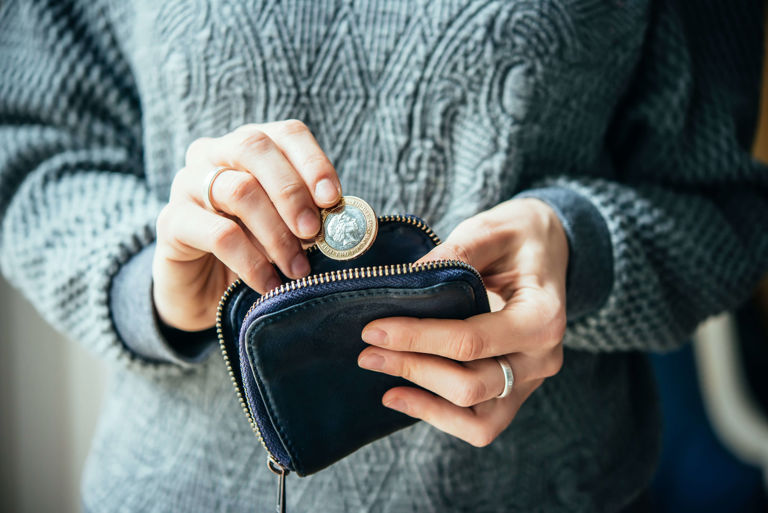 Woman putting a coin into a purse Woman putting a coin into a purse