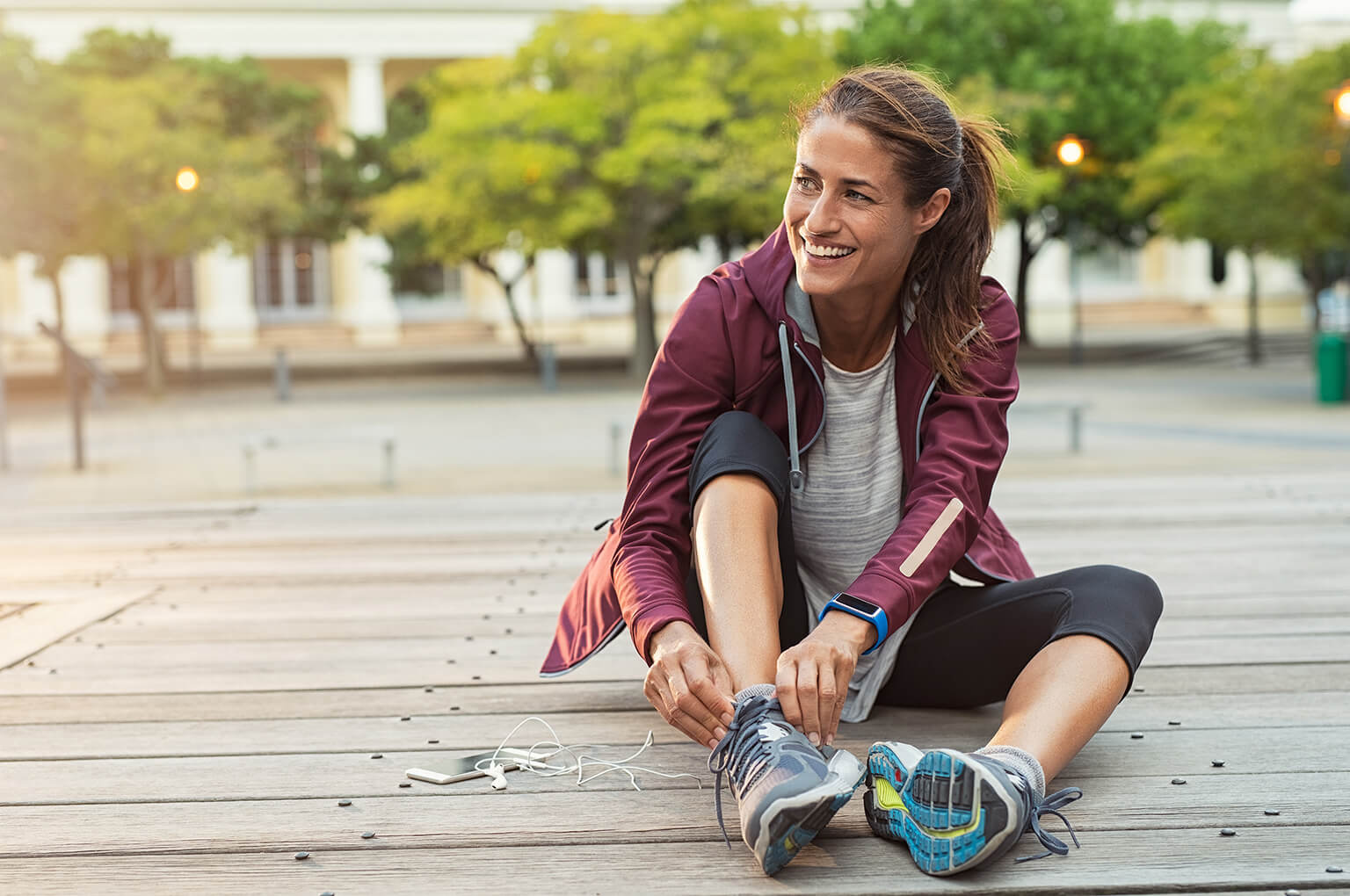 Lady sitting outdoors on the floor tying her shoelace